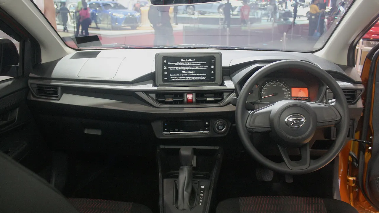 Dasbor Daihatsu Ayla 1.2 R generasi kedua dengan layar sentuh di tengah, setir berlogo Daihatsu, panel instrumen, dan tuas transmisi CVT