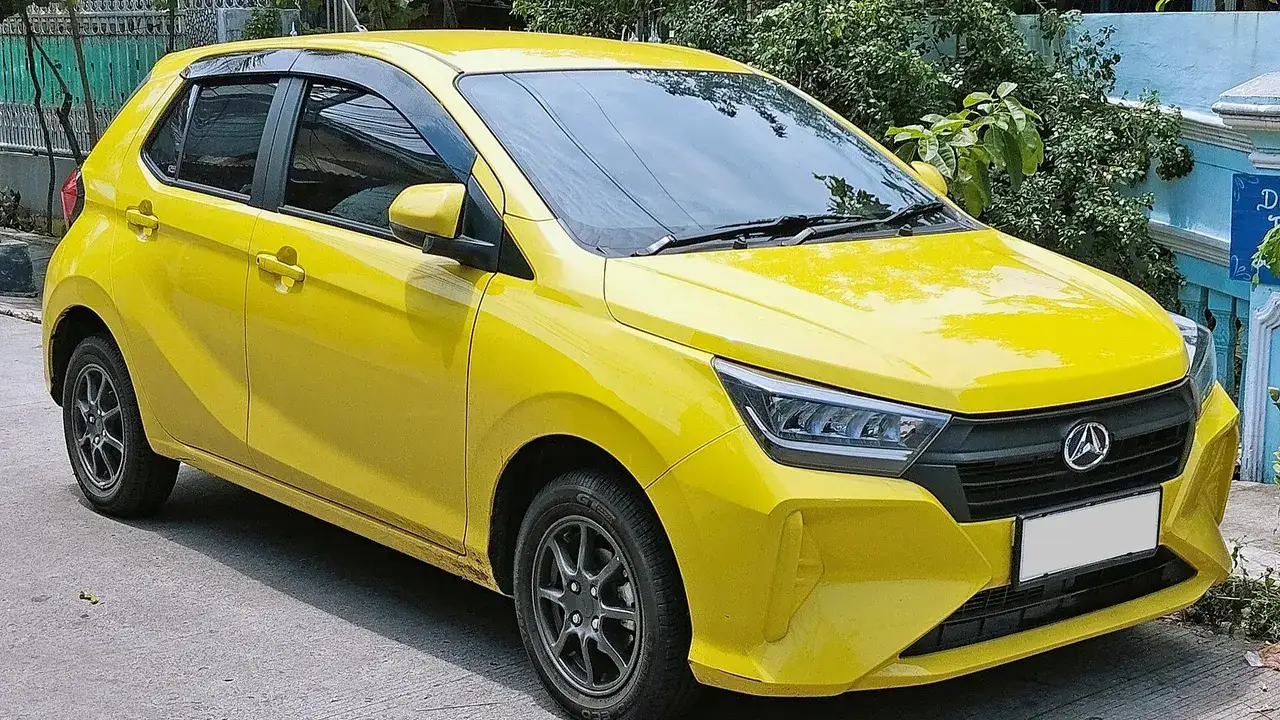 Daihatsu Ayla 1.2 R generasi kedua berwarna kuning tampak depan samping di tepi jalan, terlihat lampu utama LED, gril hitam, logo Daihatsu, dan velg alloy