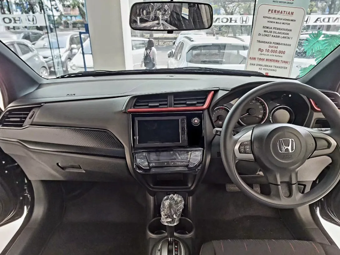 Dasbor Honda Brio RS facelift dengan aksen merah di kisi AC tengah, layar head unit, panel instrumen tiga lingkaran, setir berlogo Honda, dan tuas transmisi otomatis