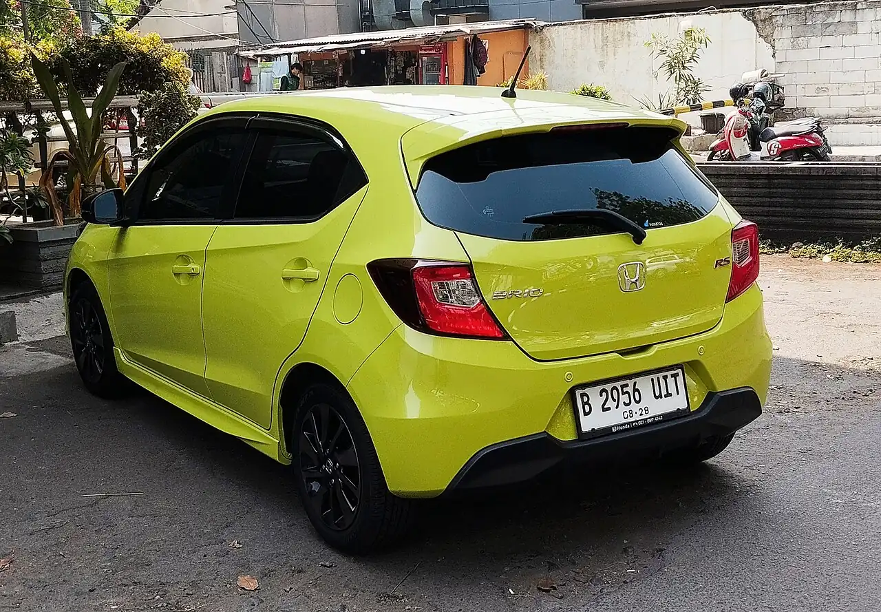 Honda Brio RS generasi kedua berwarna hijau kekuningan dilihat dari belakang kiri, dengan lencana RS di pintu bagasi, wiper belakang, dan velg berwarna gelap