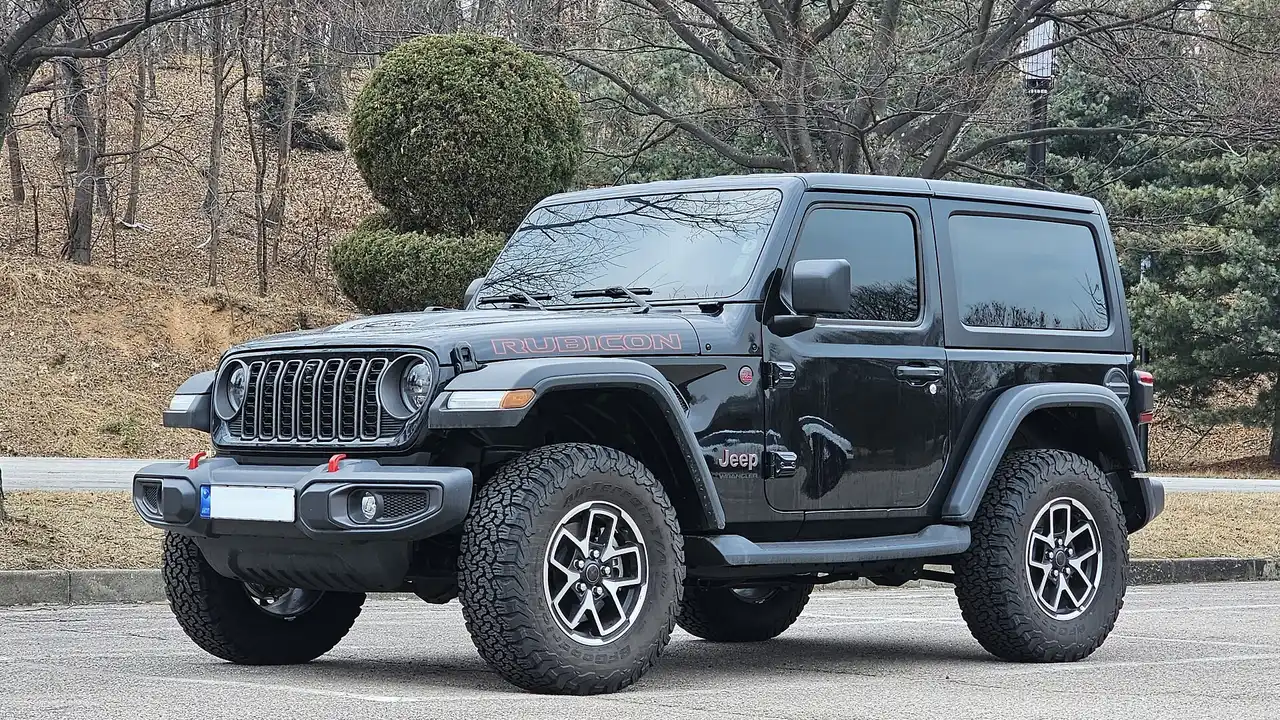 Jeep Wrangler Rubicon dua pintu generasi JL facelift berwarna hitam dengan tulisan Rubicon di kap, velg alloy, dan ban all-terrain