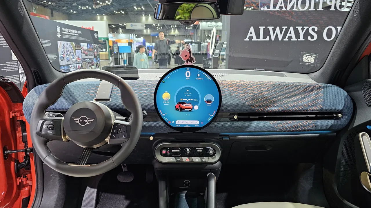 Dasbor MINI Aceman dengan layar sentuh bundar besar di tengah, setir berlogo MINI, dan panel dasbor berlapis kain rajut