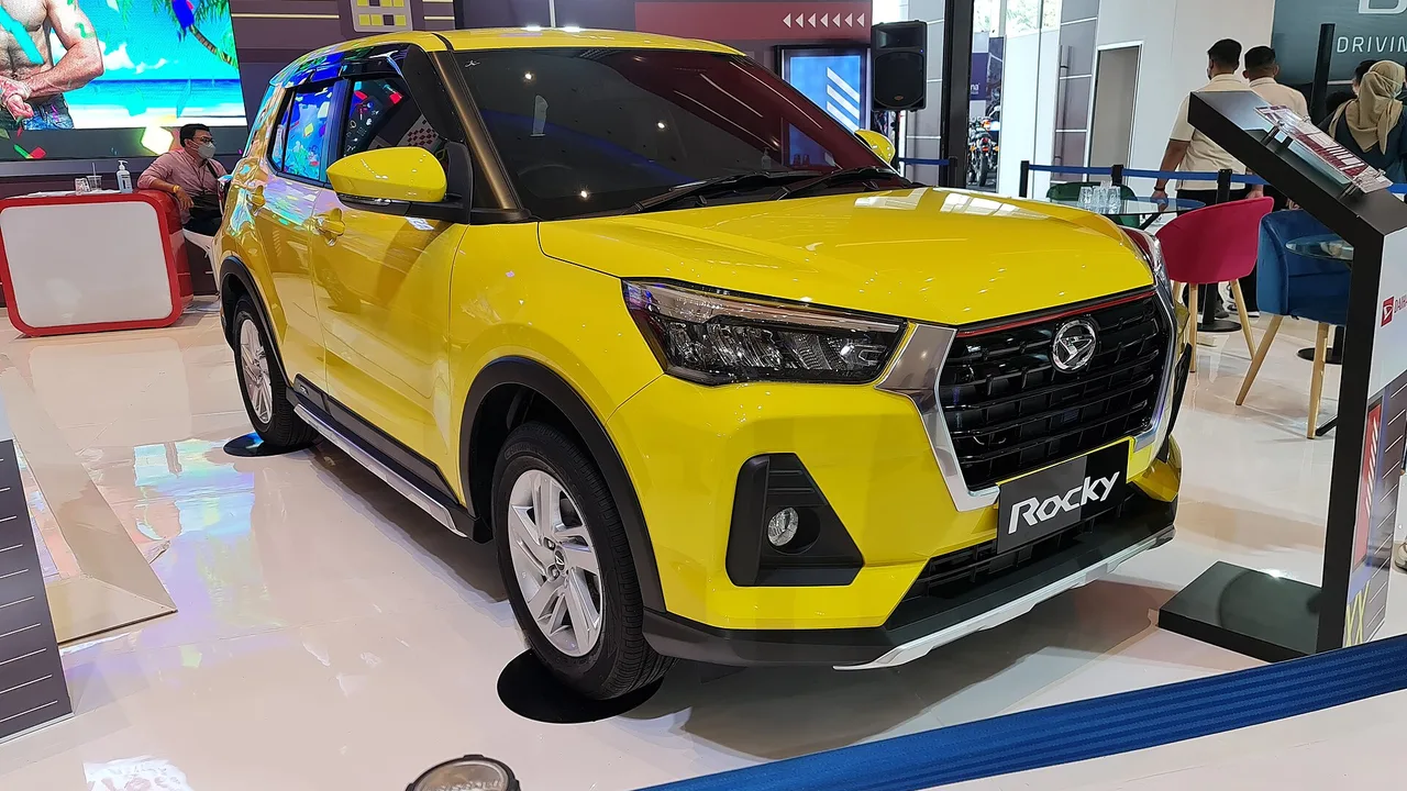 Daihatsu Rocky 1.2 X ADS berwarna kuning dengan atap hitam dipajang di area pameran, terlihat gril sarang lebah, lampu kabut, dan velg alloy 16 inci