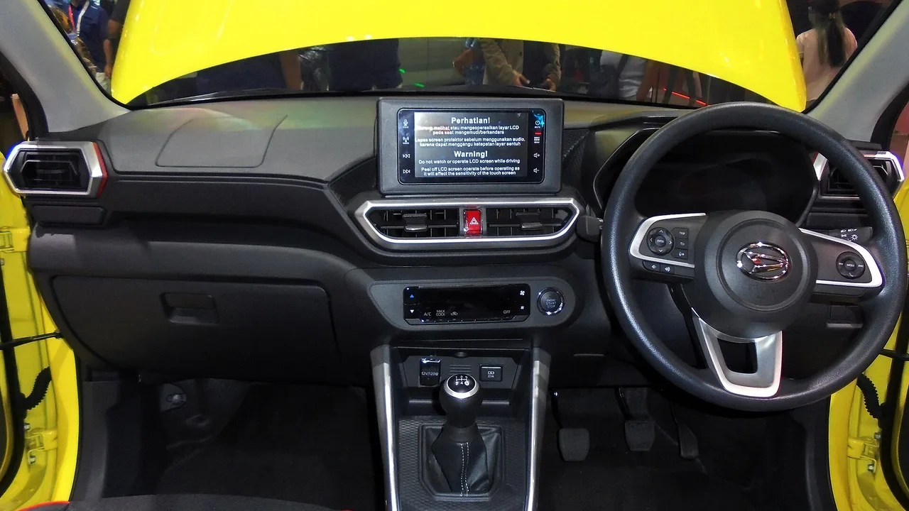 Dasbor Daihatsu Rocky 1.2 X ADS bertransmisi manual dengan setir berlogo Daihatsu, layar sentuh di tengah, dan tuas persneling lima percepatan
