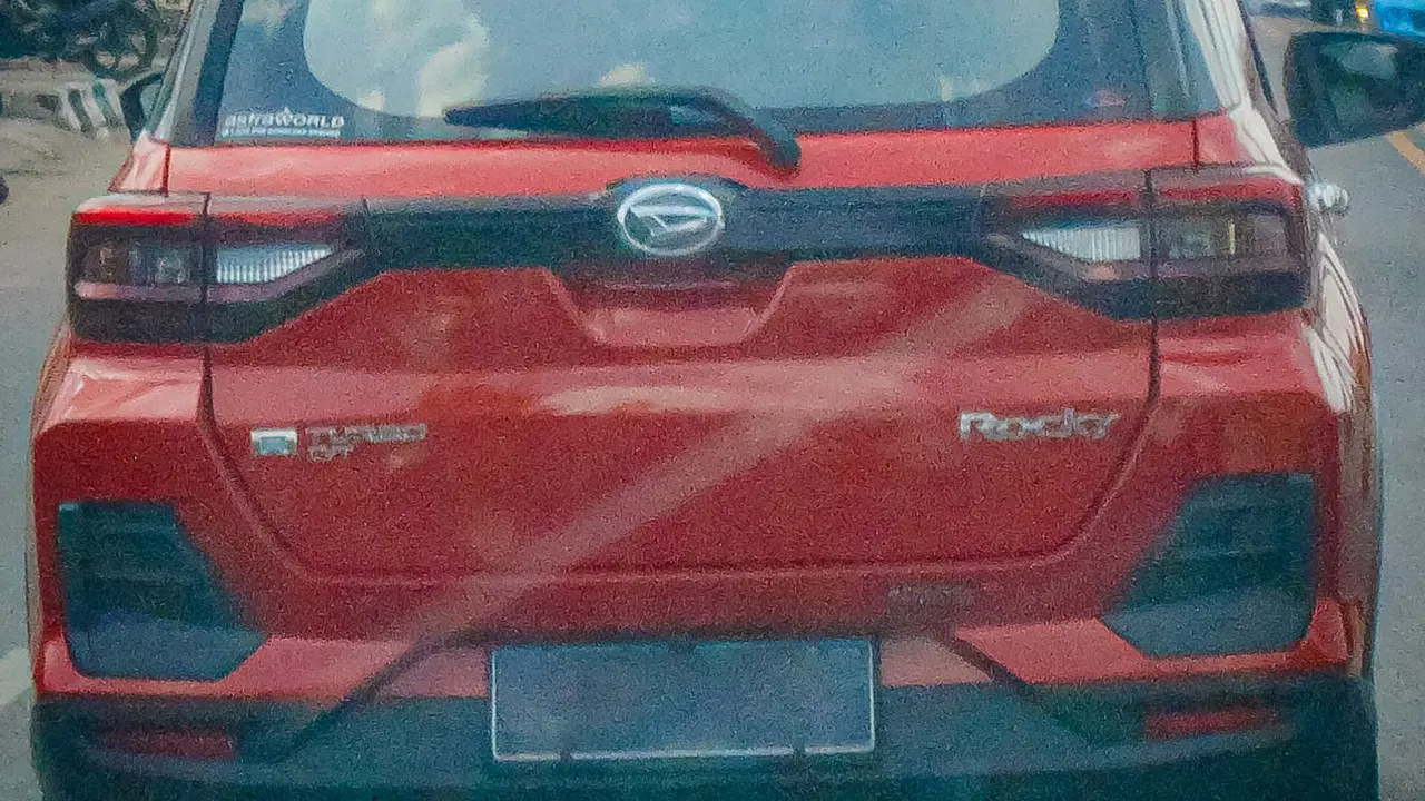 Bagian belakang Daihatsu Rocky merah di jalan raya Palembang, terlihat logo Daihatsu, tulisan Rocky, dan emblem turbo di pintu bagasi